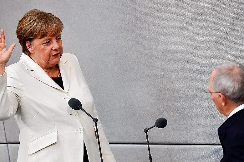 German Chancellor Angela Merkel being sworn in for her fourth term in office by the president of the Lower House of Parliament Wolfgang Schaeuble yesterday.
