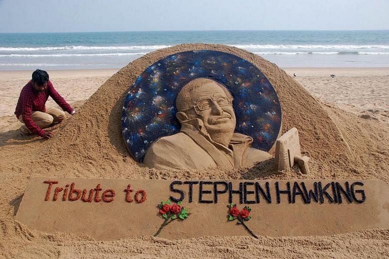 Sand artist Sudarsan Patnaik giving final touches to a sculpture at India's Puri Beach yesterday in honour of British cosmologist Stephen Hawking, who died at the age of 76 yesterday.