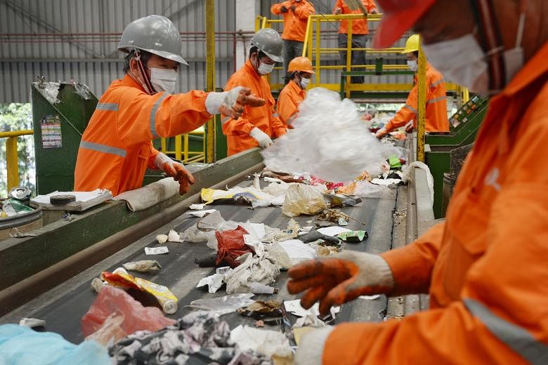 Staff at a SembWaste facility in Tuas picking out recyclable objects from trash. Recycling carries costs that are often overlooked, says the writer. For example, recycling paper could cause more severe water pollution or soil contamination as the rem