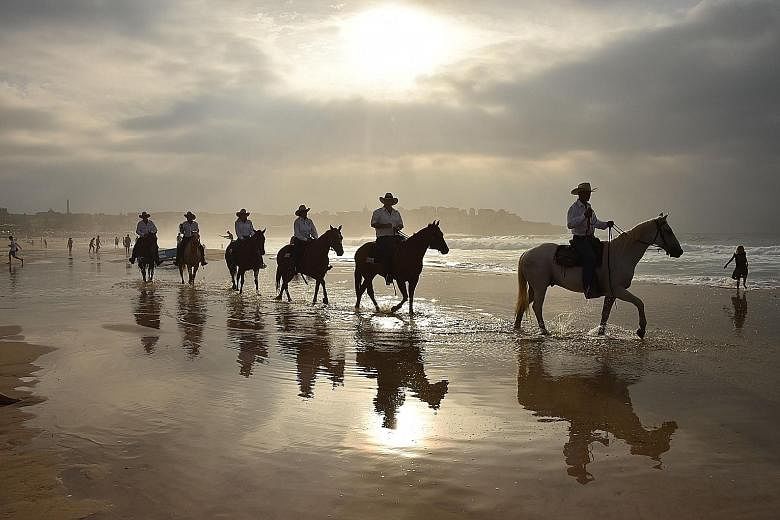 Drovers on horseback riding across Bondi Beach in Sydney yesterday. They travelled thousands of kilometres with 40 cows from the Australian outback to illustrate the struggle people living in rural and remote areas have in accessing health services.