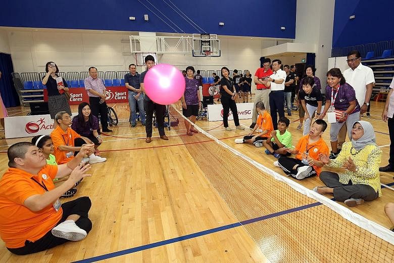 President Halimah Yacob (far right) joins a group of people with disabilities in a game of sitting volleyball as part of the Temasek Foundation Cares Play-ability programme, while Minister for Culture, Community and Youth Grace Fu provides encouragem
