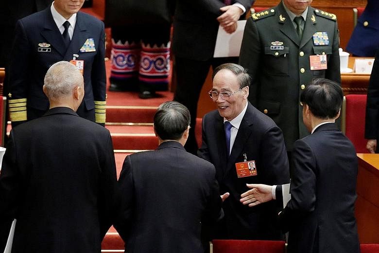 Newly-elected Chinese Vice-President Wang Qishan shaking hands with other officials after the fifth plenary session of the National People's Congress at the Great Hall of the People in Beijing yesterday.