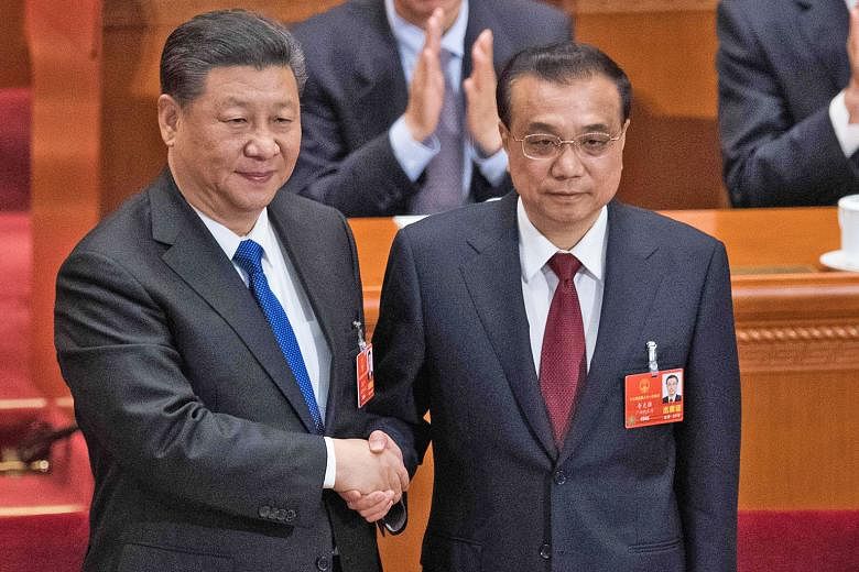 China's President Xi Jinping (left) congratulating Premier Li Keqiang after he was re-elected for a second term, at the National People's Congress held in the Great Hall of the People in Beijing yesterday.