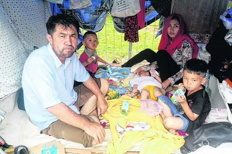 Above: A tent city has sprung up outside the detention centre, with refugees clamouring to get in. Right: Afghan Zabihullah Nazari with his family in their makeshift shelter. They arrived in Jakarta nearly four years ago but ran out of money. Outside