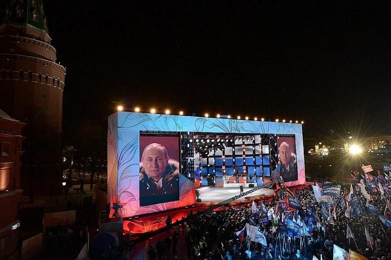 Russian President Vladimir Putin speaks to his supporters during a rally at Manezhnaya Square near the Kremlin in Moscow on Sunday. In a late-night victory speech near Red Square after the results were announced, Mr Putin told a cheering crowd the wi