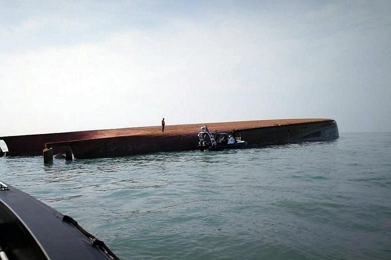 Rescuers at the site of an overturned sand-dredging vessel in the waters off southern Malaysia yesterday. One person died, while 14 others - 12 Chinese, one Indonesian and one Malaysian - were missing after the dredger capsized off Parit Jawa in Joho