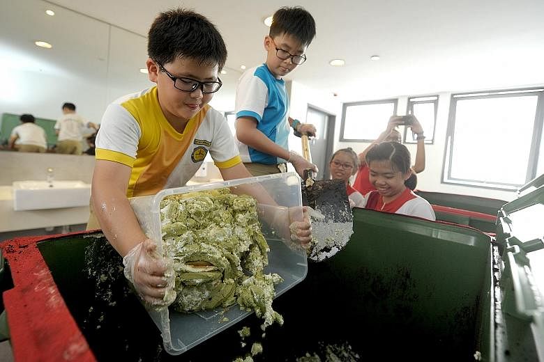 Yu Neng Primary School pupils transferring leftover cake trimmings into a bin laid with peat moss, as part of a compost-making project with BreadTalk in 2016. Every Housing Board block has been provided with a blue recycling bin - up from one bin for