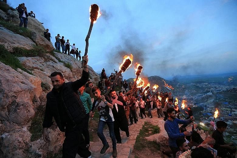 Iraqi Kurdish people carrying torches up a mountain in the Iraqi town of Akra on Tuesday, in celebration of Newroz Day. The festival, held on the spring equinox, marks the arrival of spring and the new year. It is considered the most important festiv