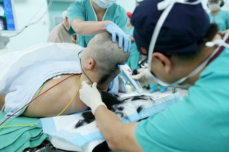 Associate Professor See asking Mr Oh to raise his right arm to test his movement. Awake brain surgery is done in less than 10 per cent of brain tumour cases at the institute, when surgeons need to operate on an area of the brain that involves or is c