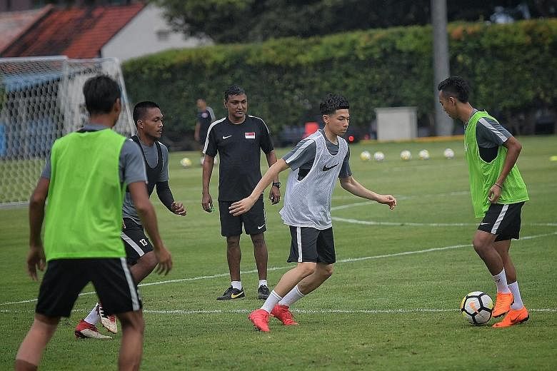 Ben Davis of Fulham Under-18s, who earned his first national team call-up, closing down PKNS player Faris Ramli in training as coach V. Sundram Moorthy observes. There are 10 overseas-based players in the squad.