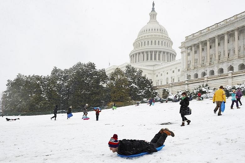 Visitors sledding down the hillside near the US Capitol in Washington (above), while flights were cancelled at Reagan National Airport (below) in Arlington, Virginia, on Wednesday, as heavy snow hit the United States north-east. The wintry blast on t