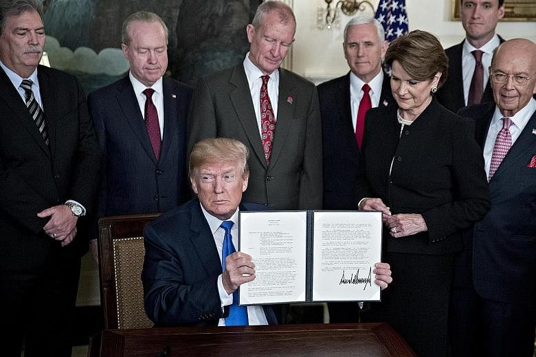 US President Donald Trump holding a signed presidential memorandum on US tariffs on Chinese imports, surrounded by business leaders and members of his administration, in the White House on Thursday. A trade war between the two economic giants will no