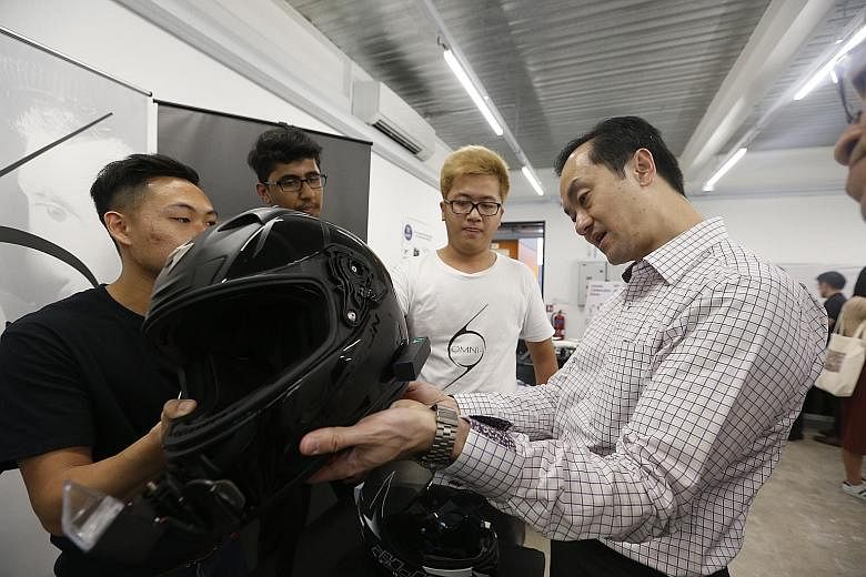 Dr Koh Poh Koon looking at an OMNi-smart helmet, which is made by OMNI-, a start-up firm supported by the Robotics Centre. It is fitted with information display, GPS navigation, dual-view camera and in-built speakers, and can be controlled by a mobil