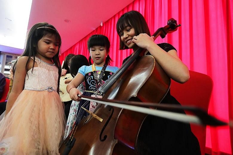 Professional musician Terresa Huang, 28, giving pointers on how to play the cello. For many of the children, it was their first time seeing such instruments. Professional musician Kevin Cheng, 28, playing the sheng at the Red Bean Concert yesterday. 