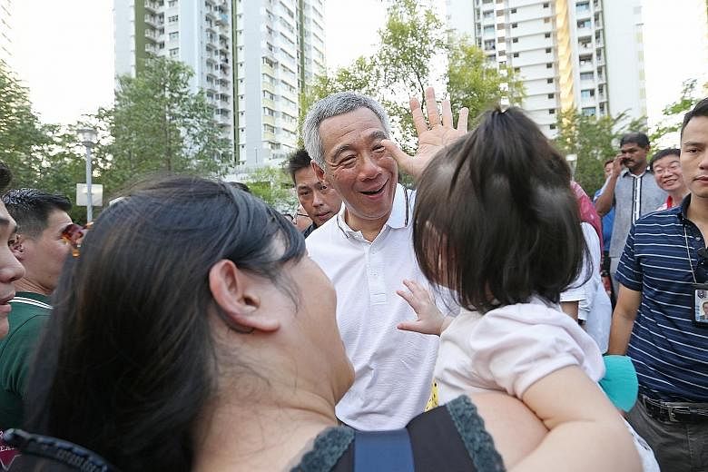 Prime Minister Lee Hsien Loong greeting a baby and her mother at the Kids and Babies Carnival in Sengkang South yesterday. The new facilities were planned after collecting feedback from residents.