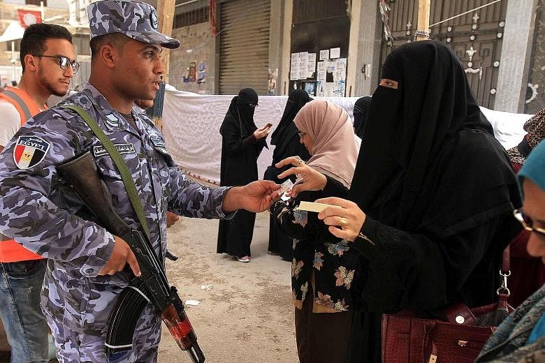 An Egyptian naval conscript checking the identification document of a voter before letting her enter a polling station in Alexandria yesterday. Tight security was enforced, with police and soldiers deployed at polling stations a day after a bomb atta