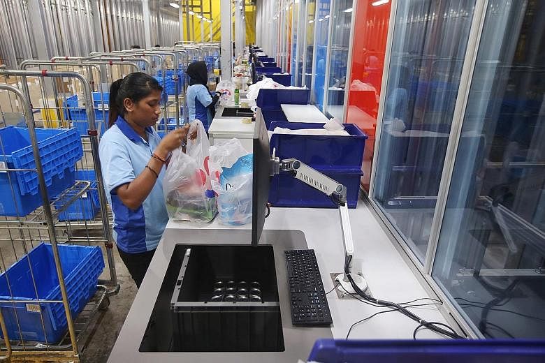 Pickers at the FairPrice Hub distribution centre bagging items for online orders. The new system is four times faster than the old one, which required pickers to retrieve items manually.