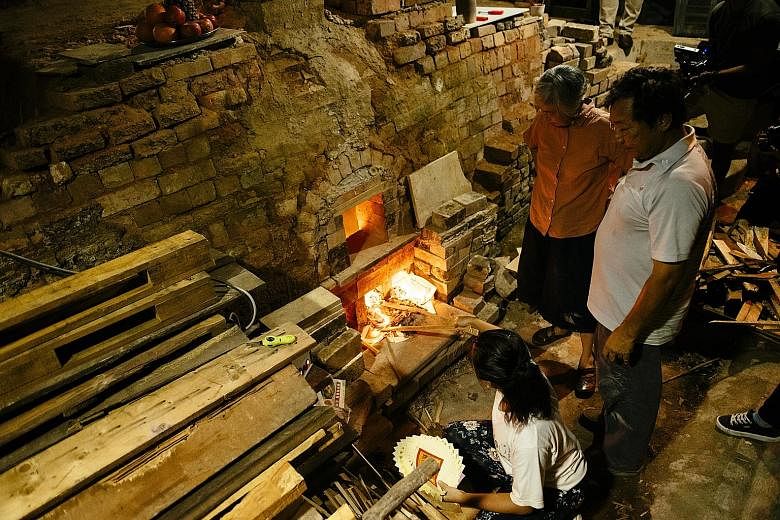 Ms Stella Tan, 27, stokes the fire at the last operational dragon kiln in Singapore, while family members Yulianti Tan, 59 (in pink), and Tan Teck Yoke, 61, look on. The kiln, located in the family-run Thow Kwang Pottery Jungle in Jalan Bahar, was bu