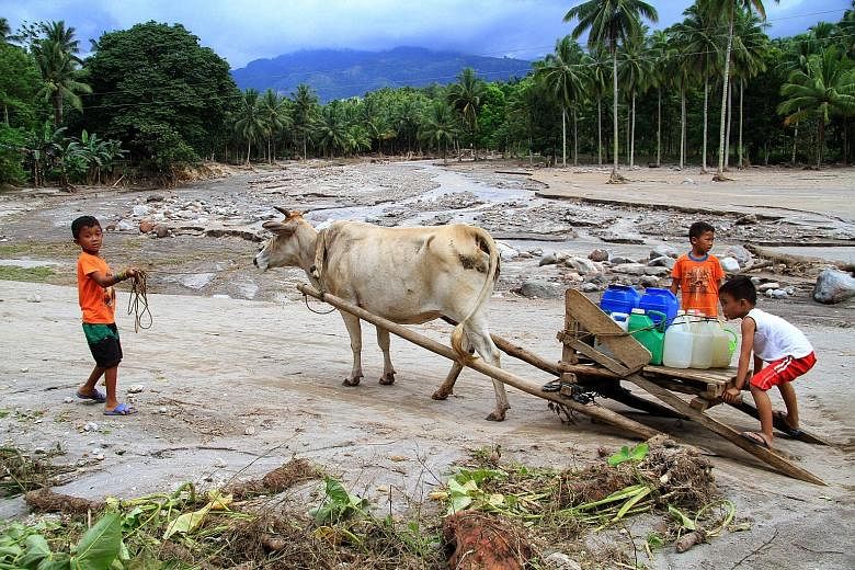 Children transporting drinking water on a makeshift carriage in a village hit by flash floods in Lanao del Norte province in the Philippines. The country is highly vulnerable to the effects of climate change. Farming and fishing communities are disap