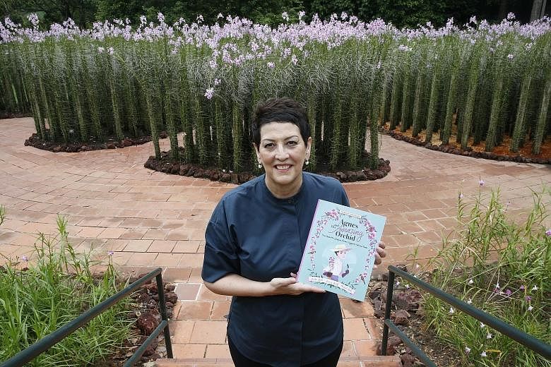 Ms Linda Locke, the great grandniece of Agnes Joaquim, at the Botanic Gardens with her book titled Agnes And Her Amazing Orchid. Behind her are displays of the Vanda Miss Joaquim, originally cross-bred by the horticulturist in the 19th century.