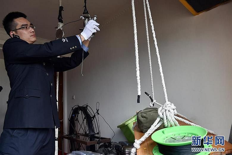 A police officer showing the tools used by a smuggling gang to set up a cable linking two high-rise apartments on opposite sides of the mainland-Hong Kong border. A power-driven winch was then used to transport cellphones across the cable link. A sma