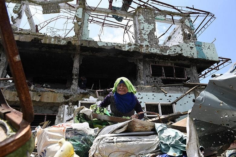 An anguished resident trying to collect salvageable belongings from her destroyed house during a visit yesterday to the main battle area in the southern Philippine city of Marawi. After fleeing for their lives nearly a year ago, residents of the batt