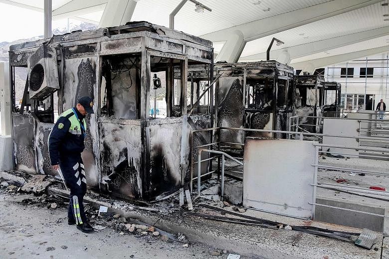 An Albanian police officer inspecting charred toll booths at the Durres-Kukes highway, which links Albania and Kosovo, last Saturday. The booths at the Morina border crossing were set alight by protesters after a decision to introduce a toll on the h
