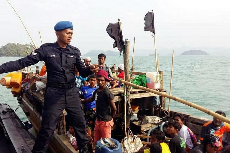 A Malaysian Maritime Enforcement Agency officer on the boat carrying Rohingya refugees, after it was intercepted off Langkawi yesterday. The coast guard said there were 19 men, 17 women, 12 girls and eight boys on the boat. The vessel was first seen 