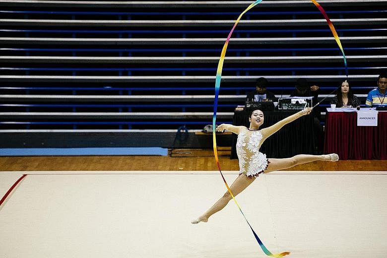 Natalie Ho of Raffles Girls' School executing her ribbon routine at the National School Games rhythmic gymnastics championships at Bishan Sports Hall yesterday. She won the C Division Level 4 event with 7.100 points. RGS completed a double when Berni