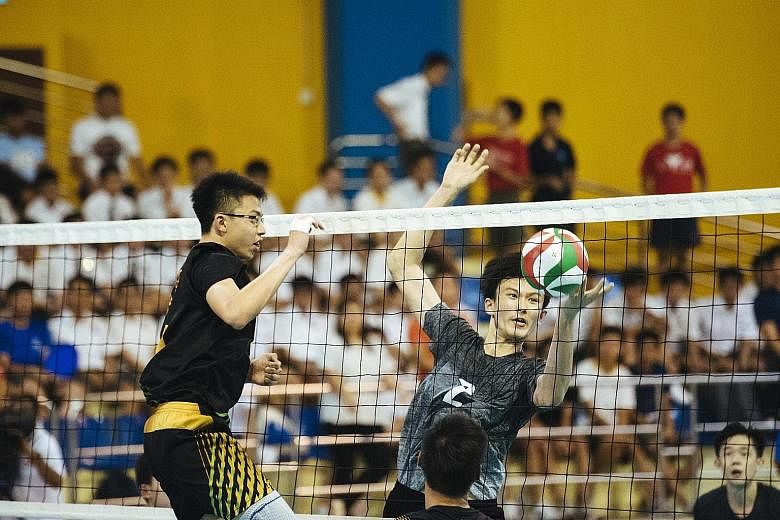 Avan Cheah (left) and Jaron Lee of St Hilda's Secondary blocking a spike from Catholic High's Alastair Chan in the B Division volleyball final at Woodlands Sports Hall yesterday.