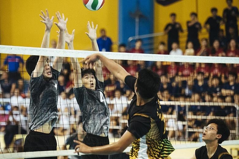 Avan Cheah (left) and Jaron Lee of St Hilda's Secondary blocking a spike from Catholic High's Alastair Chan in the B Division volleyball final at Woodlands Sports Hall yesterday.