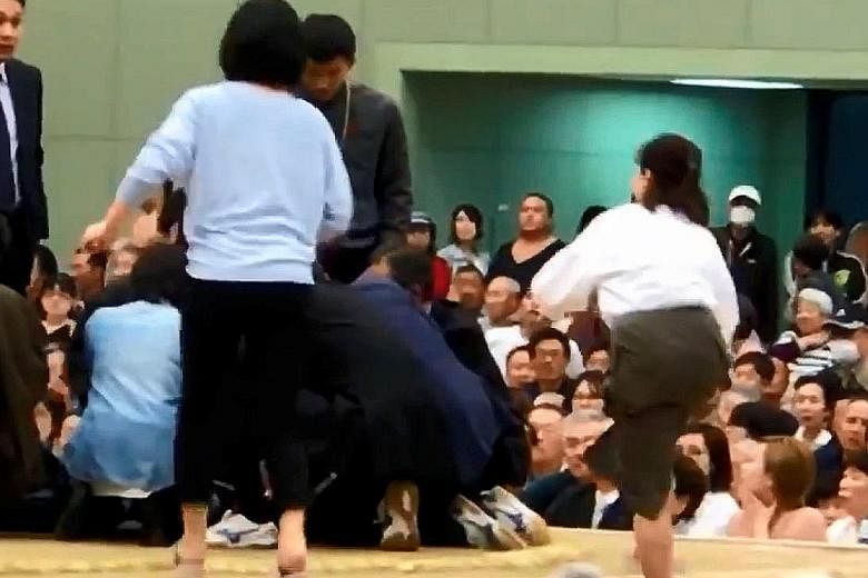 A photo grab from a Youtube video showing women in a sumo ring helping Maizuru mayor Ryozo Tatami, who collapsed while making a speech. Women are forbidden from entering the ring, which is regarded as sacred.