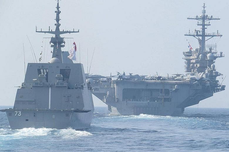 The RSS Supreme Formidable-class frigate (left) sailing in formation with the USS Theodore Roosevelt aircraft carrier. They are taking part in a passage exercise between the Singapore and US navies.