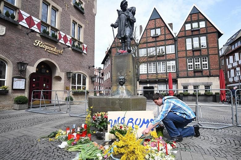 A man placing flowers yesterday at the scene in the inner city of Muenster, Germany, where a van had driven into people sitting outside a restaurant on Saturday.