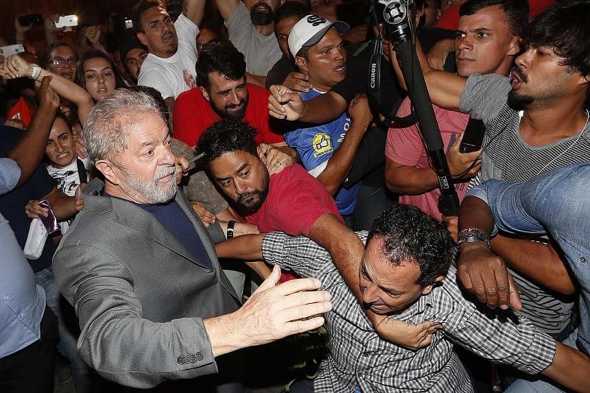 Luiz Inacio Lula da Silva (at left) leaving the steel workers' union headquarters in Sao Bernardo do Campo on Saturday as supporters tried to prevent his exit. The former president entered police custody to begin serving a 12-year prison sentence for