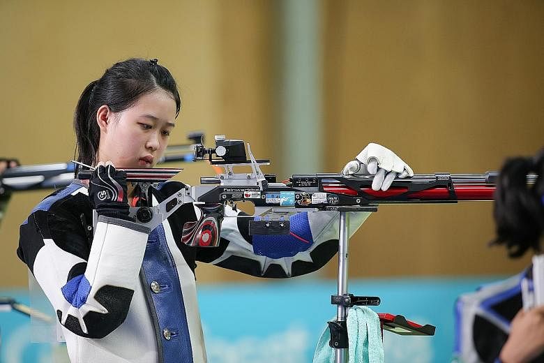 Left: Martina Veloso celebrating with her 10m air rifle gold medal yesterday. She won a single-shot shoot-off against India's Mehuli Ghosh after the duo finished tied first on 247.2 points. Below: Tessa Neo trying to fix her rifle in the midst of the