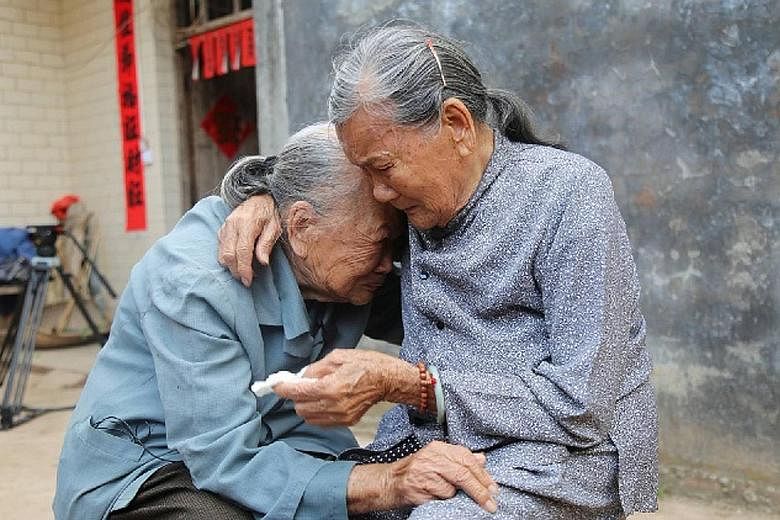 Madam Que Bamei (far right), 87, with her half-sister Qijie. When they met each other on March 29, after being separated for 79 years, they held each other and cried for a long time without uttering a word.