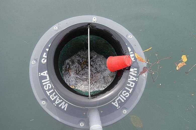Left: Seabin Project chief executive Pete Ceglinski installing a seabin at the Republic of Singapore Yacht Club in West Coast yesterday. Above: The seabin can catch about 1.5kg of debris and litter a day, as well as microplastics. It can also collect