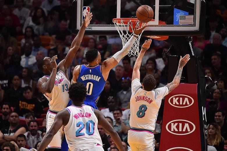 Oklahoma City point guard Russell Westbrook evading the challenges of Miami's Edrice Adebayo and Tyler Johnson for a finger roll. The Thunder sealed their post-season spot with a 115-93 win at the American Airlines Arena.