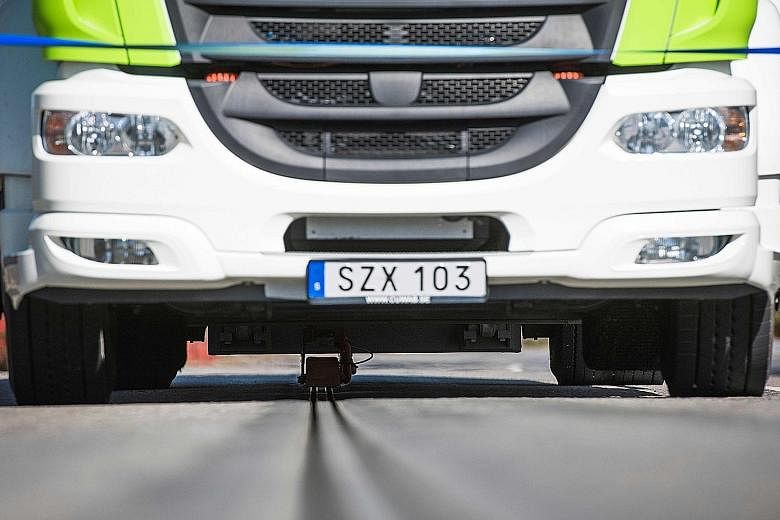 An electric truck on the world's first electrified road at Sweden's Stockholm Arlanda airport on Wednesday. Energy is transferred from two tracks of rail in the road through a movable arm attached to the bottom of the vehicle. When the vehicle stops,