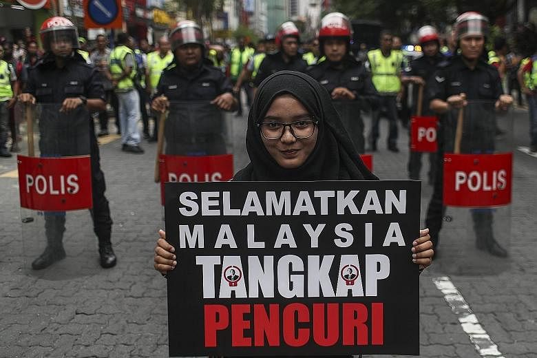 A protester holding a placard during the #Tangkap-Pencuri (Nab A Thief) rally in Kuala Lumpur, Malaysia, yesterday. The rally is being held to call for the arrest of financier Low Taek Jho - better known as Jho Low - and "thieves" linked to the finan