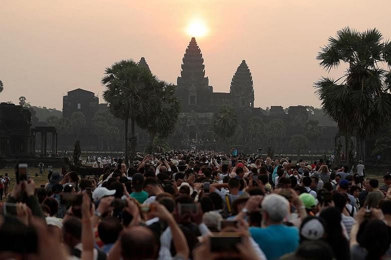 Huge crowds are drawn to the majestic sight of the sun rising over the central stupa of the famous Angkor Wat temple in Siem Reap, Cambodia, in this photo taken on March 22 this year. A rubbish collector clearing trash on the polluted Kuta beach near
