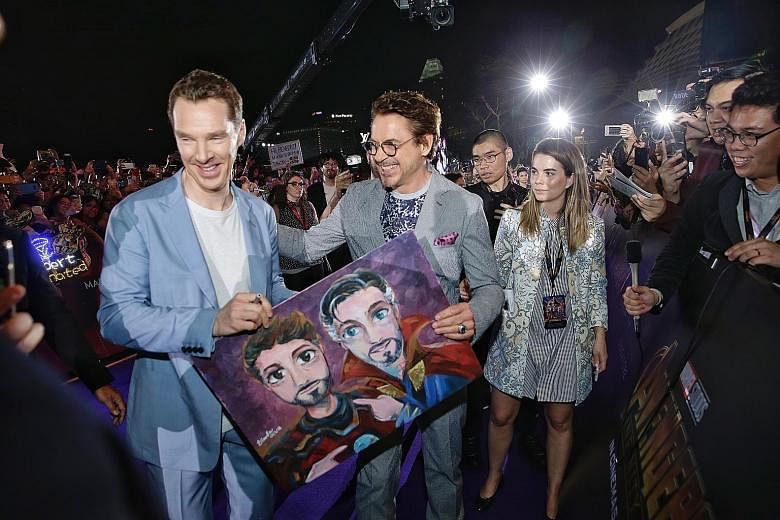 Actor Benedict Cumberbatch (far left), who plays Doctor Strange in the upcoming film Avengers: Infinity War, and Robert Downey Jr, who plays Iron Man, with a drawing of their characters by a fan, at the movie's red-carpet fan event at the Marina Bay 