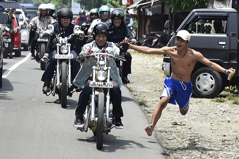 An enthusiastic Indonesian running to connect with President Joko Widodo, in a show of support for the country's top leader. Mr Joko and his entourage were on a 30km motorbike tour of the rural areas of Sukabumi in West Java last week.