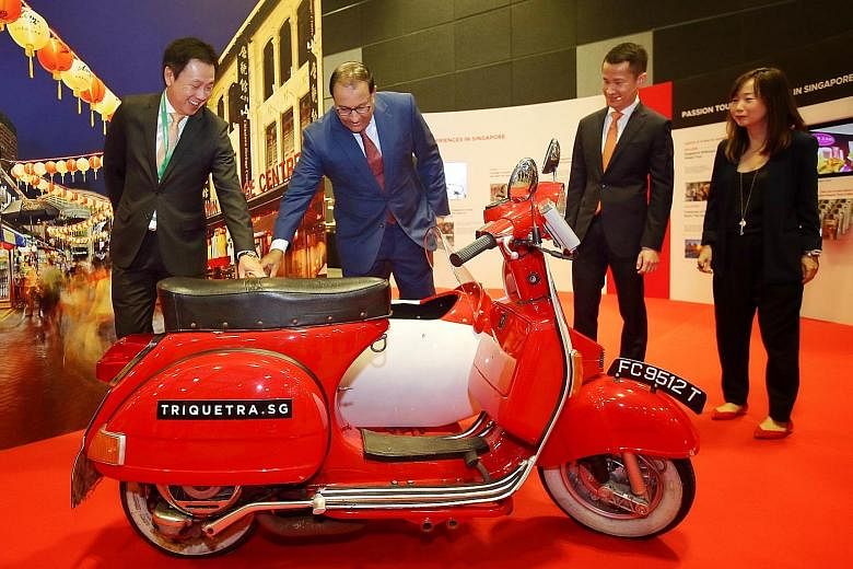 Minister for Trade and Industry (Industry) S. Iswaran looking at a vintage Vespa with a sidecar at the marketing and technology showcase at the Tourism Industry Conference 2018. With him are (from left) STB chairman Chaly Mah, chief executive Lionel 