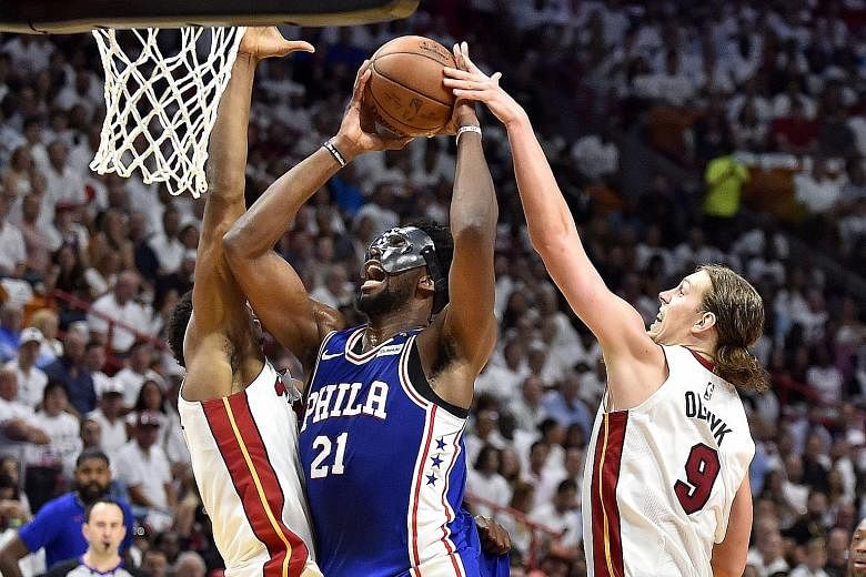 Joel Embiid of the Philadelphia 76ers drives to the basket while being defended by Hassan Whiteside (left) and Kelly Olynyk. Embiid scored 23 points in the Sixers' 128-108 win in Game 3.
