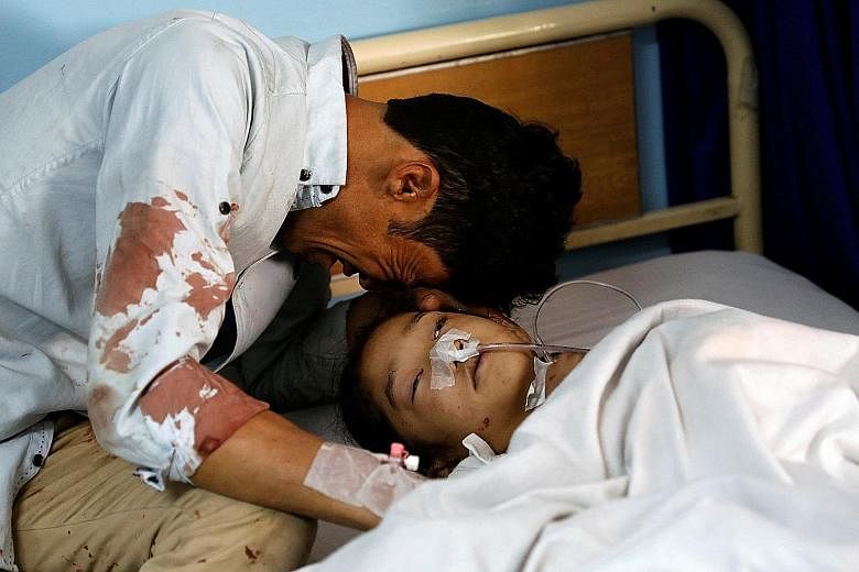 A man crying beside an injured girl at a hospital after the attack in Kabul, Afghanistan.