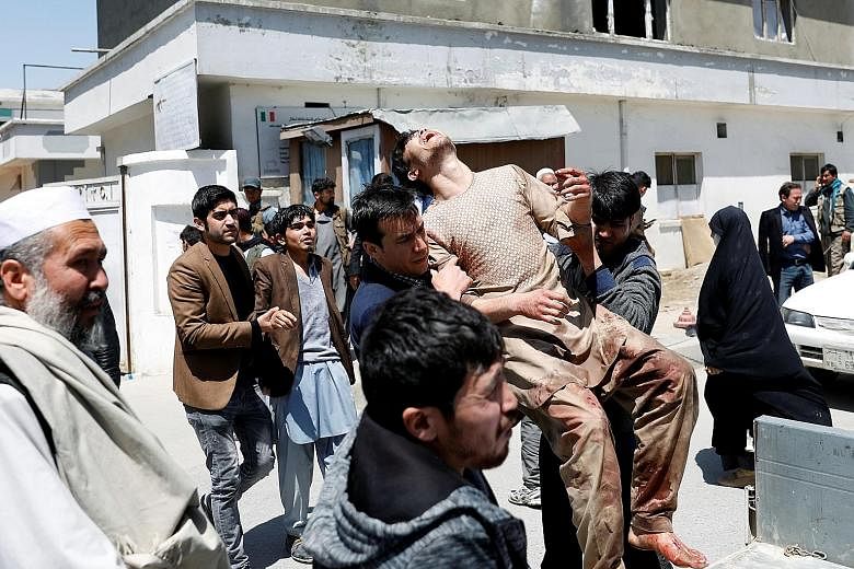 Relatives carrying an injured man to hospital following a suicide attack outside a voter registration centre in the Afghan capital Kabul yesterday. Some 112 people were wounded in the blast.