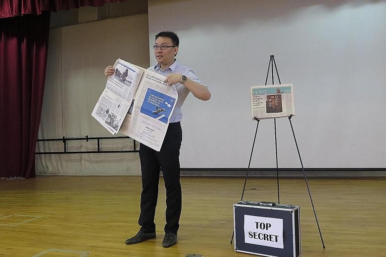 Mr Edwin Wan holding up a copy of The Straits Times as he unveils his predictions during a session in Yio Chu Kang Primary School last Wednesday. The head of the English language department hopes to motivate pupils to want to find out more about thin