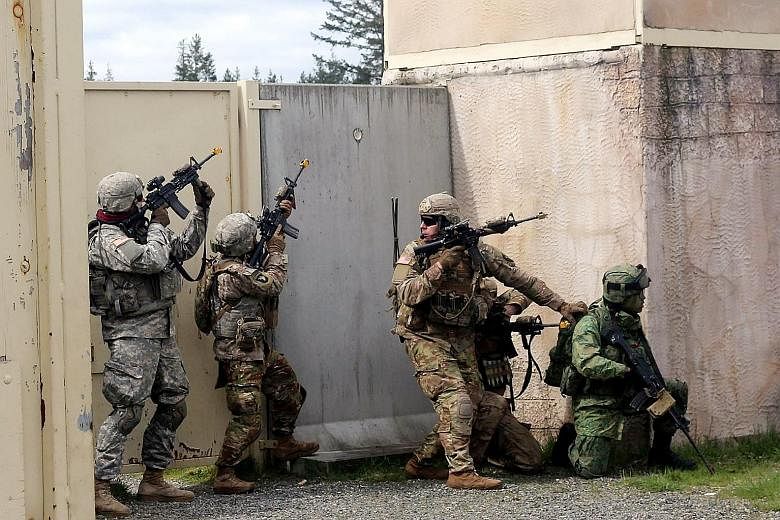 Soldiers from the Singapore and United States armies performing an integrated battalion assault on an urban objective during Exercise Lightning Strike 2018, which was held at Joint Base Lewis-McChord, Washington, from April 16 to 24.